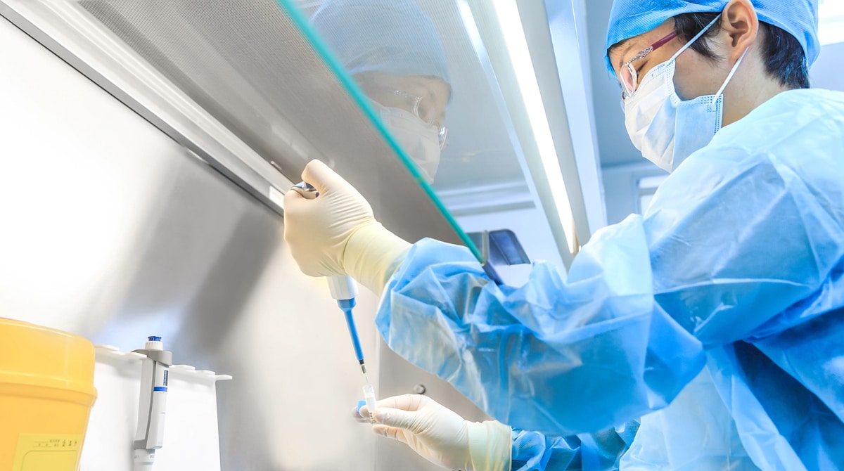China Laboratory Scientist with personal protective equipment at a laboratory using a pipette.