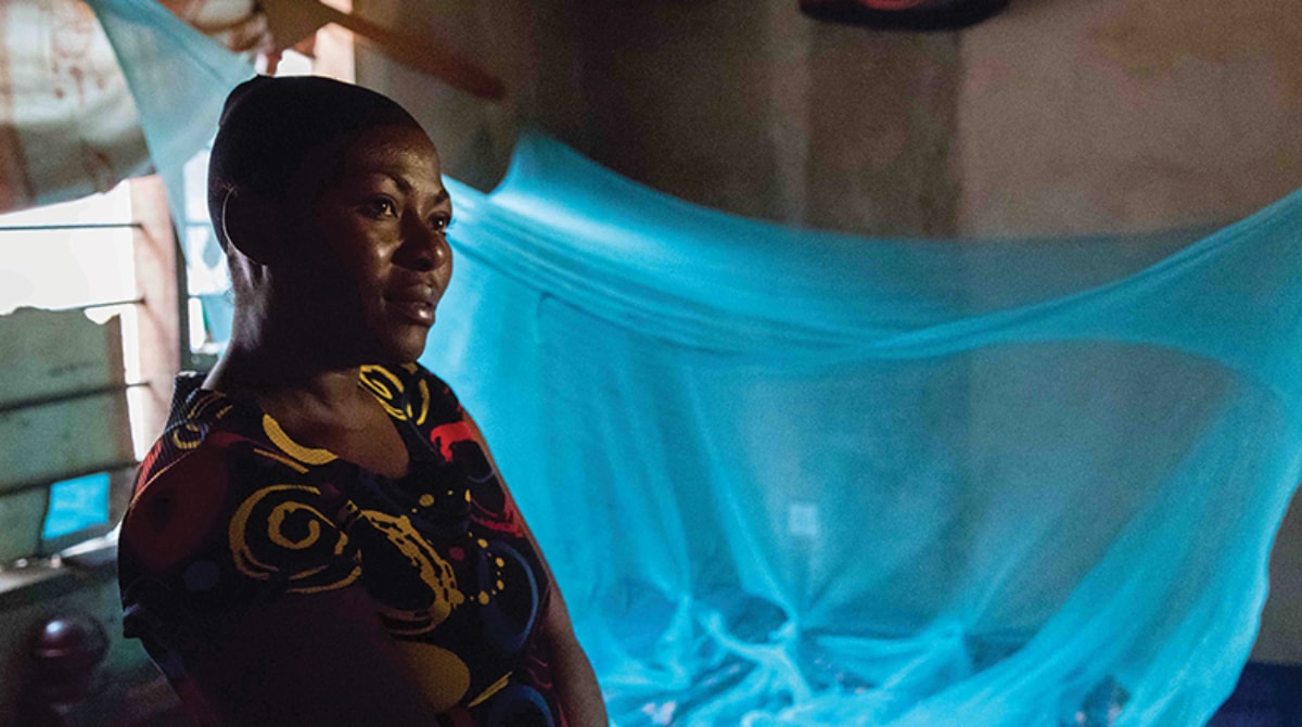 Mosquito_Prevention_16x9 Woman stands in front of mosquito bed net used for malaria prevention in Tanzania