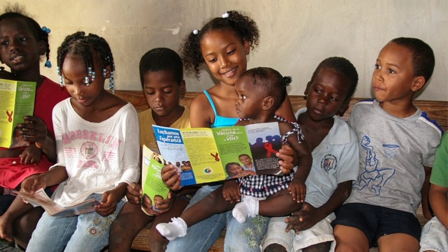 — title missing — Group of children sit on a bench and look at pamphlets