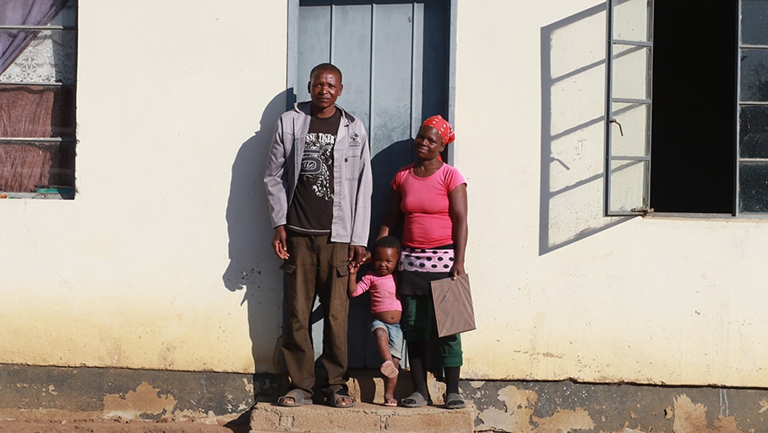 Family poses in front of home with blue door.