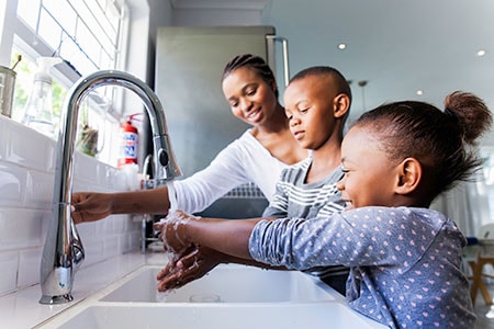 Family washing their hands together at the kitchen sink