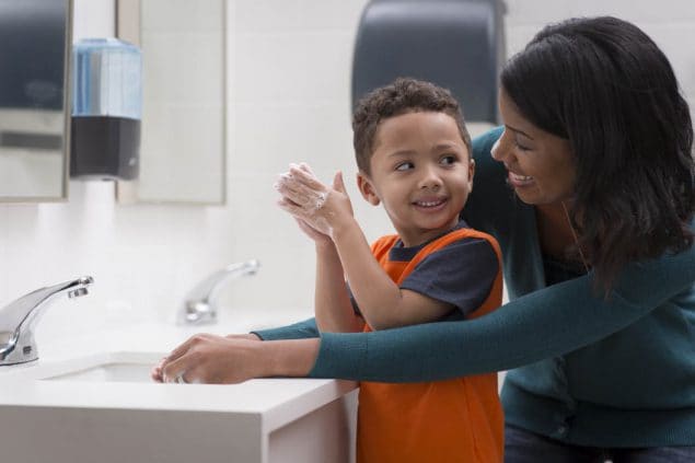 Mother helping son wash his hands