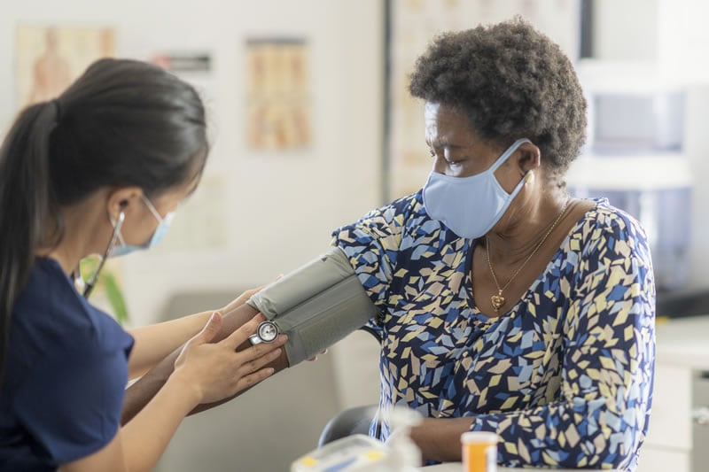 Female medical professional checking senior patient's blood pressure Profesional médico revisando la presión arterial de una paciente