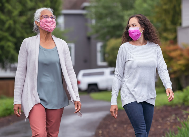 Two women wearing protective face masks enjoying the outdoor… Dos mujeres que llevan mascarilla caminando afuera