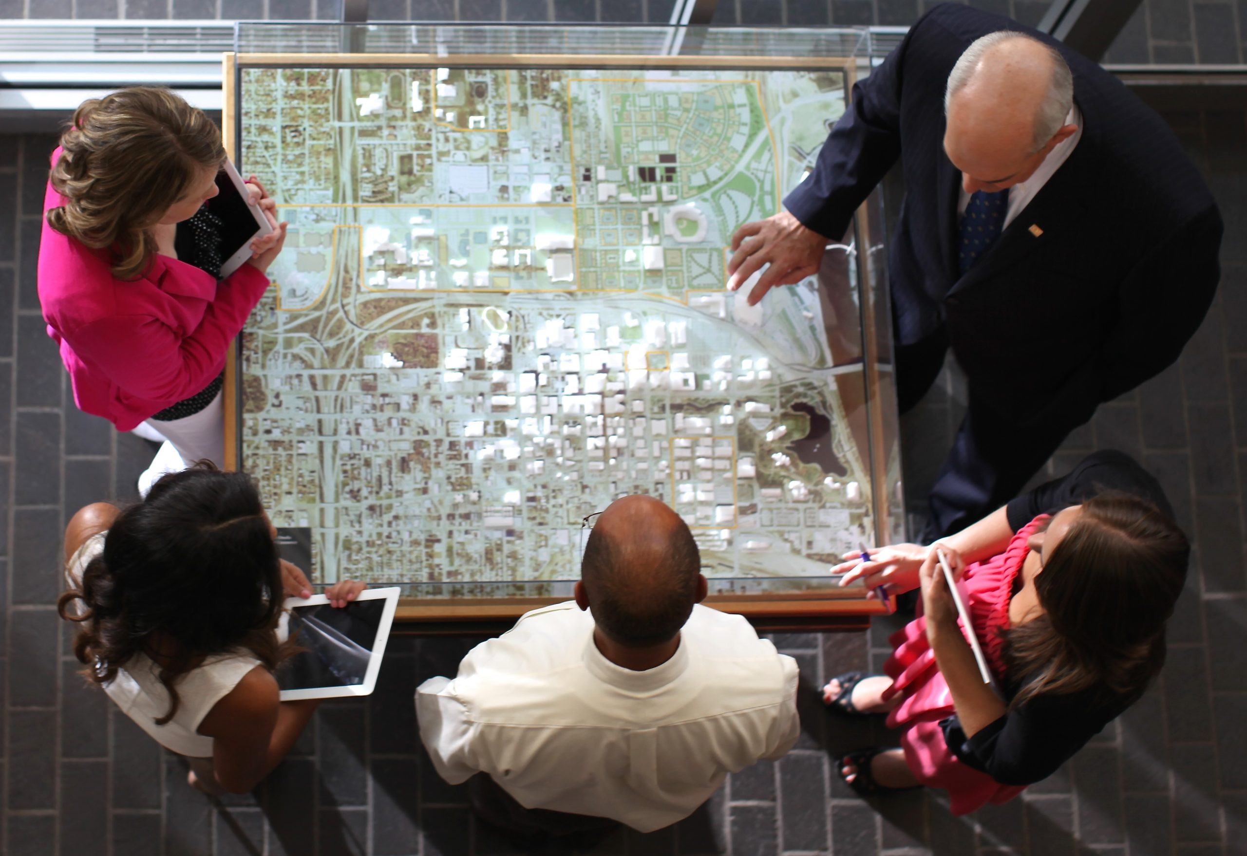 Health Impact Assessment Planning People standing around and looking at a model of a city.