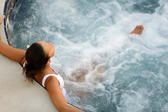 Woman sitting in a hot tub with her back to the camera.