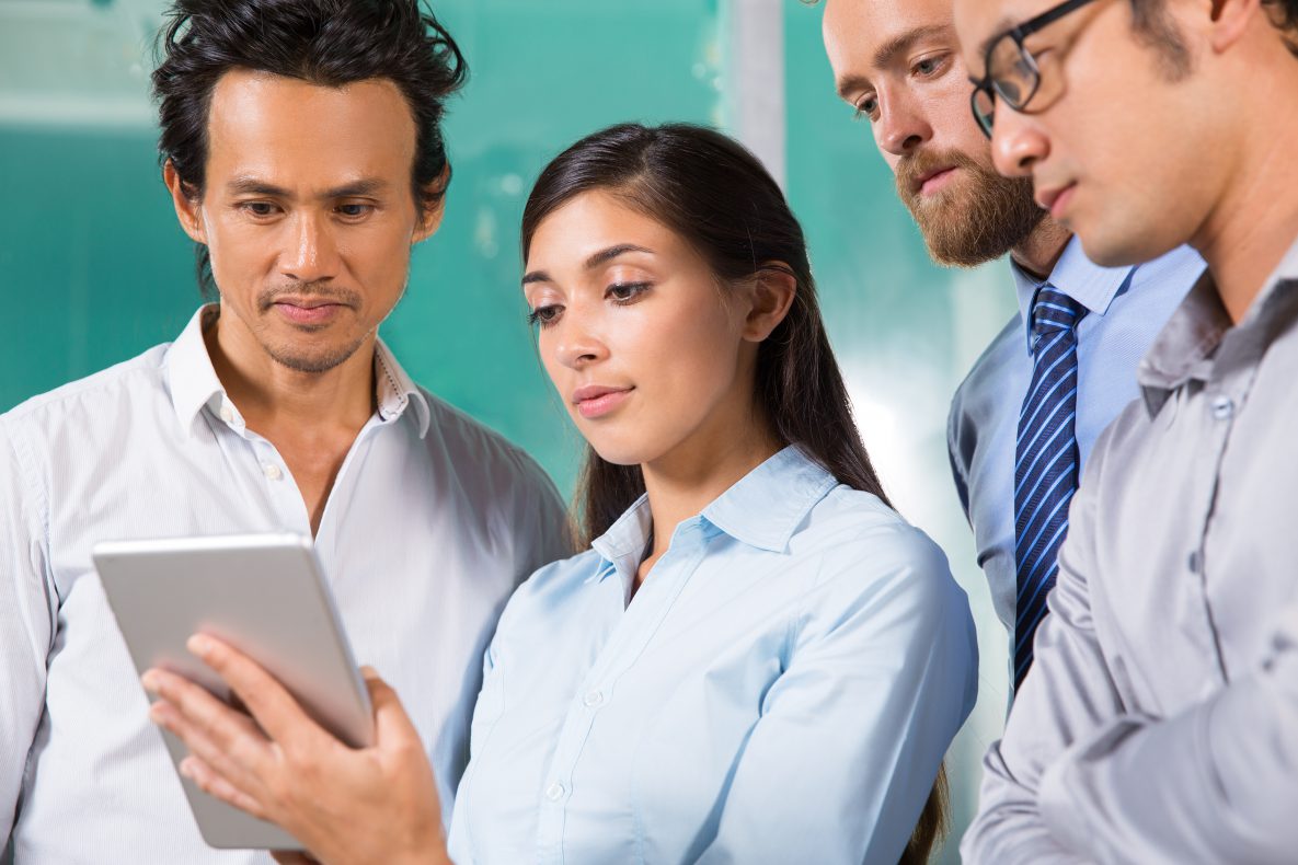Four people share information via an iPad.