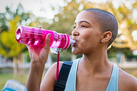 A lady drinking water from a water bottle.