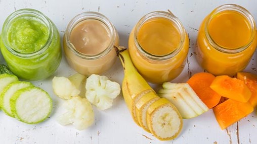 fruit and vegetables in jars Assorted fruits and vegetables cut up into chunks, placed by small jars containing pureed versions of the same food.