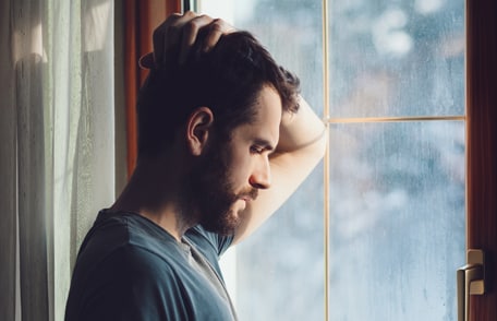 Image of a young man standing by a window