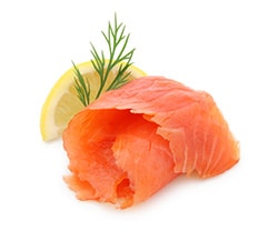 prevention-smoked-seafood A piece of smoked salmon with a sprig of dill and a slide of lemon.