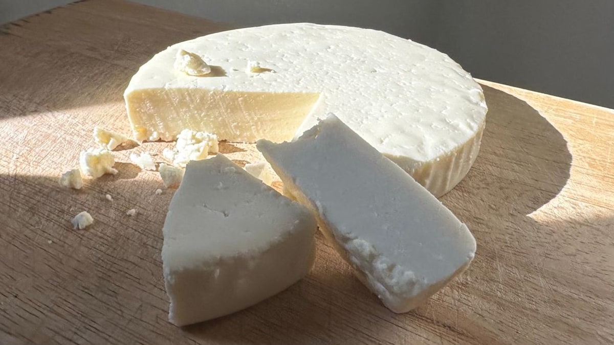 Round block of cheese on a wooden cutting board