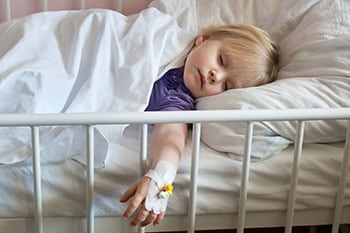 sick-child-iv Sick child laying in bed with an IV