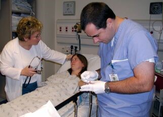patient-with-fever Patient in a hospital bed being attended to by a doctor and nurse