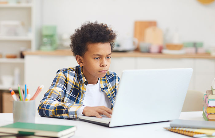 Helping children adjust to changes in school Portrait of young teenage African boy using laptop while studying at home