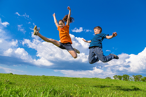 two-children-jumping-green-hills Two children jumping on green hills