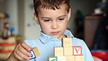 Study to Explore Early Development Autistic boy building with blocks stock photo