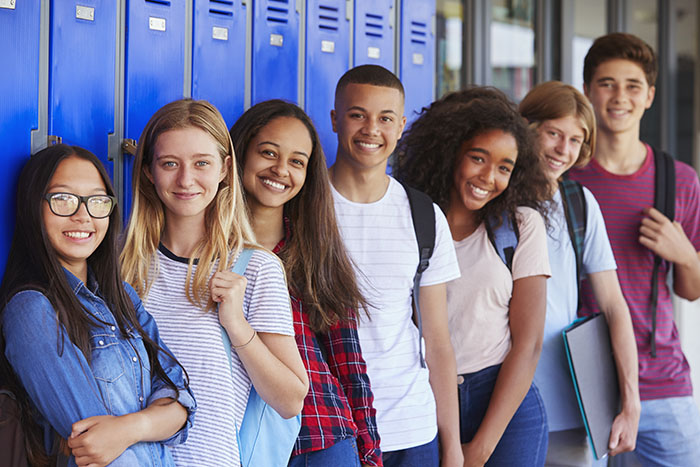 Teenage school kids smiling to camera in school hallway Teenage school kids smiling to camera in school hallway