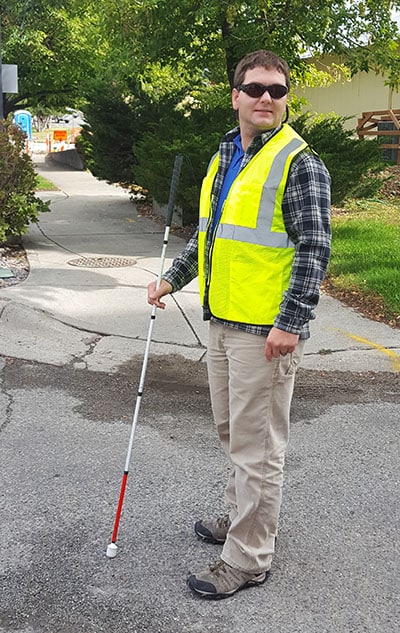 Blind man with walking stick wearing safety vest Blind man with walking stick wearing safety vest