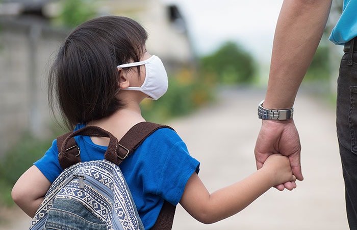 little-girl-holding-hands-with-father-700px Little girl with backpack wearing cloth face mask hand in her father's hand waiting for school bus. Children need help with the transition back to school.