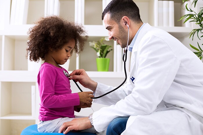 Doc-and-child Doctor bending down to listen to a little girl's heart
