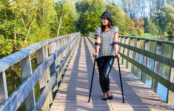 woman-walking-with-crutches A young woman walking with crutches in the park
