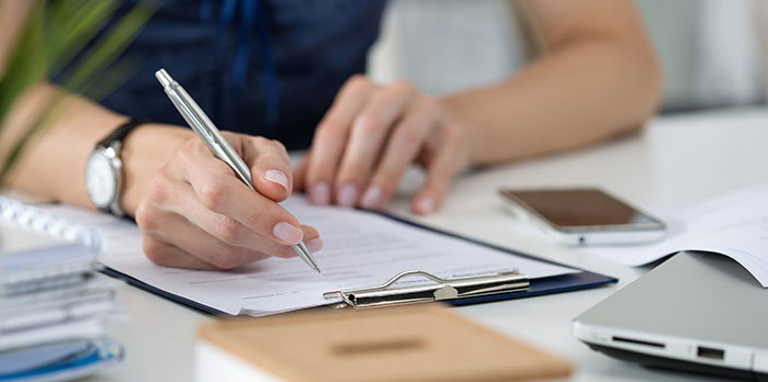 Woman writing on clipboard sitting at her office Woman writing on clipboard sitting at her office