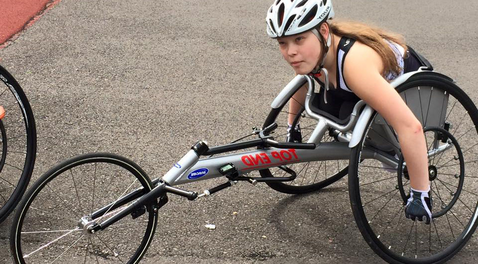 Living with Spina Bifida Young woman in wheelchair racing bike.