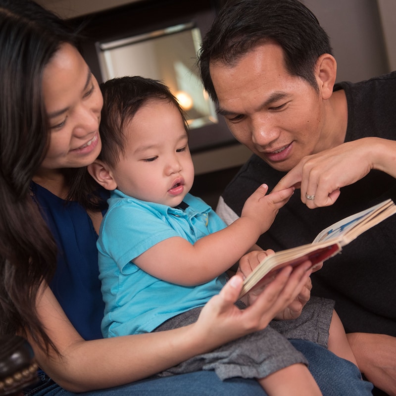 Ni?o mirando un libro con sus padres