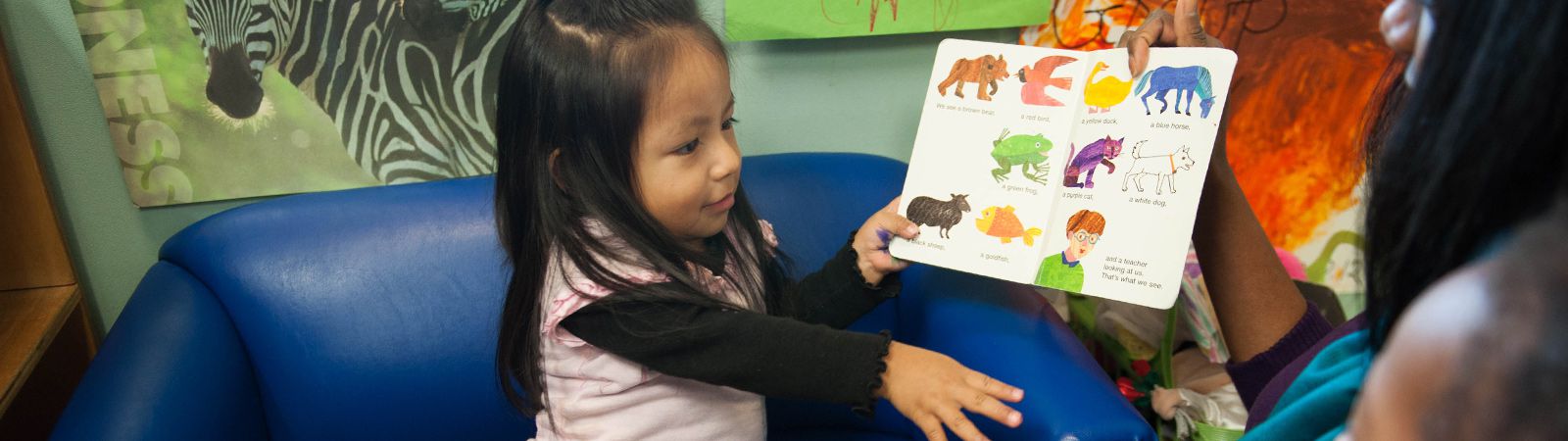 Una peque?a identifica los animales de un libro.