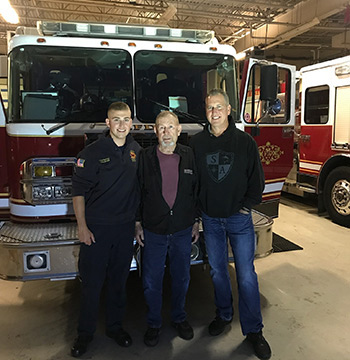 Three generations of Michigan firefighters in the fire station in front of a fire truck. Three generations of Michigan firefighters in the fire station in front of a fire truck.