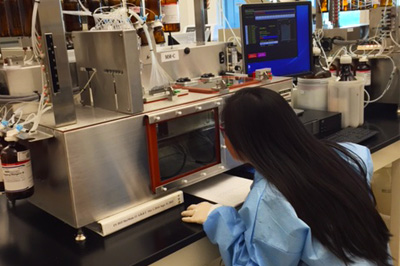 Imagen de una mujer observando la pantalla de un computador mientras trabaja en un laboratorio de los CDC