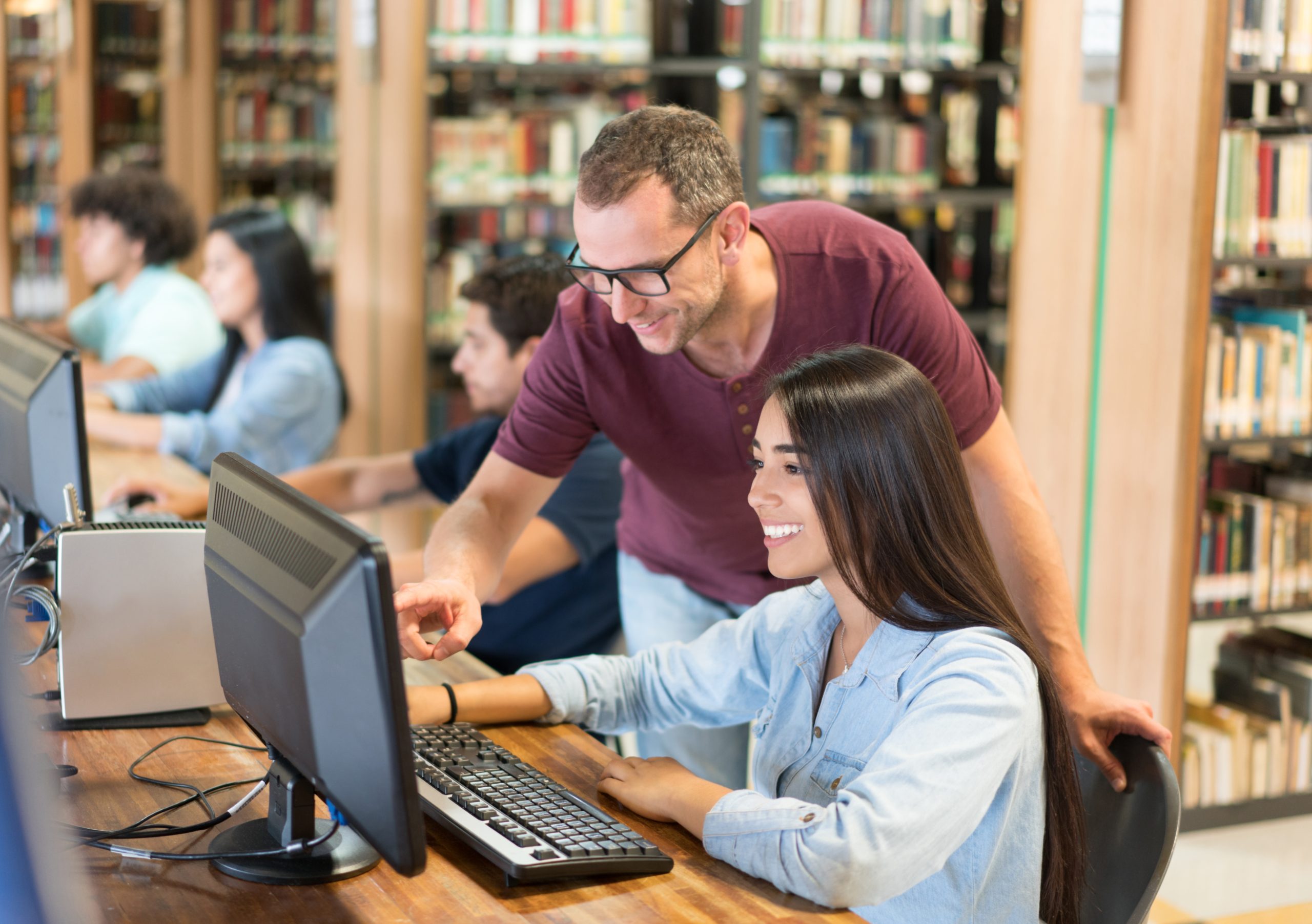 Teacher helping students at the library Teacher helping students at the library