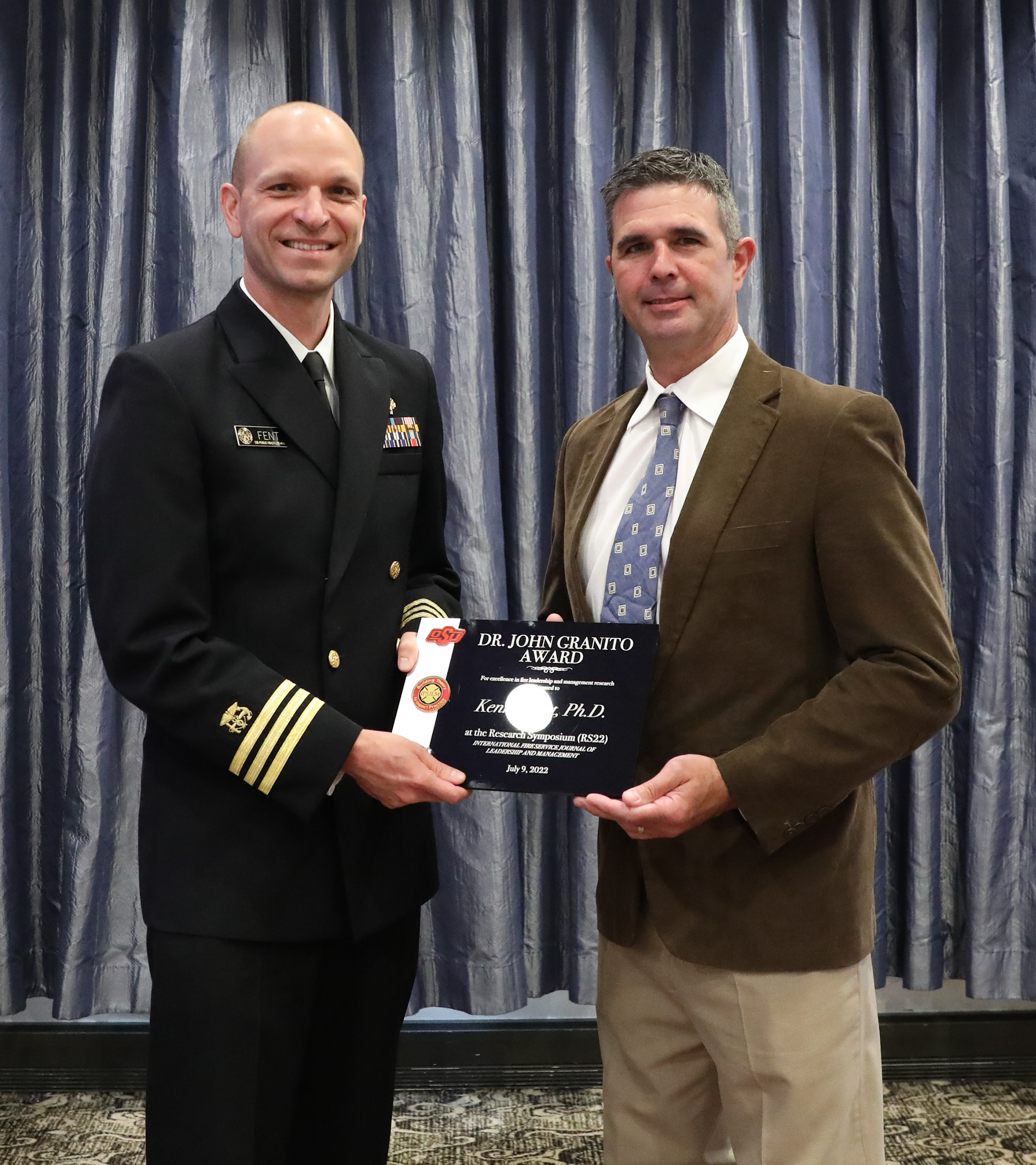 enews20n5 Dr. Kenny Fent (left) receives his award from Dr. Gavin Horn from the Underwriters Laboratories, Fire Safety Research Institute. Photo courtesy of the International Fire Service Training Association.