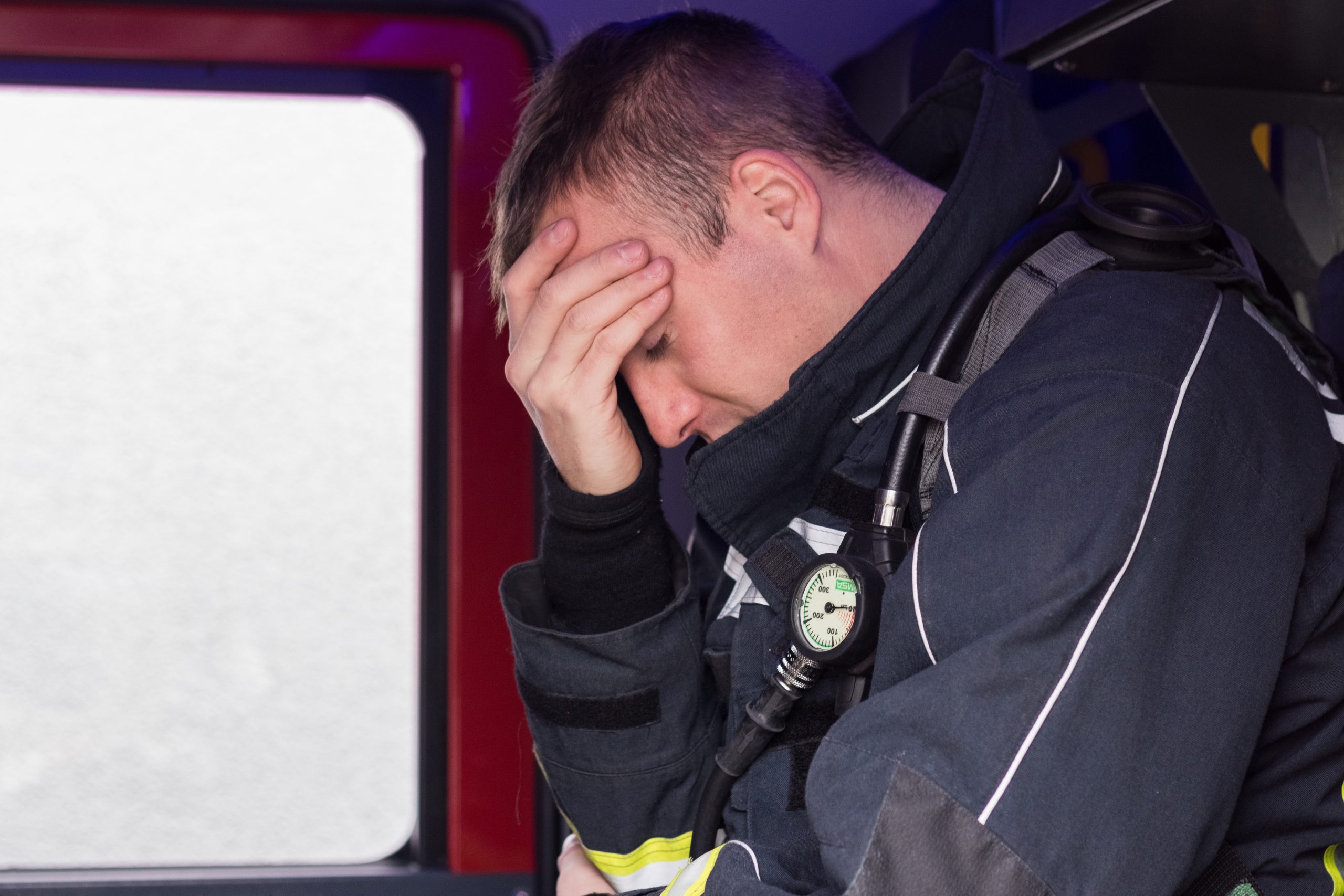 Fireman sitting on fire truck tired and sad Fireman sitting on fire truck tired and sad