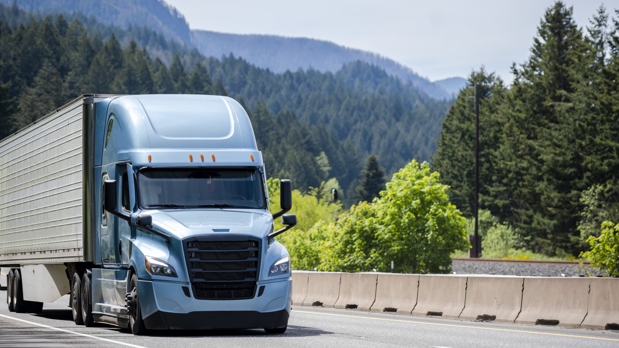 long-haul truck driver A blue semi-tractor trailer driving through the mountains.