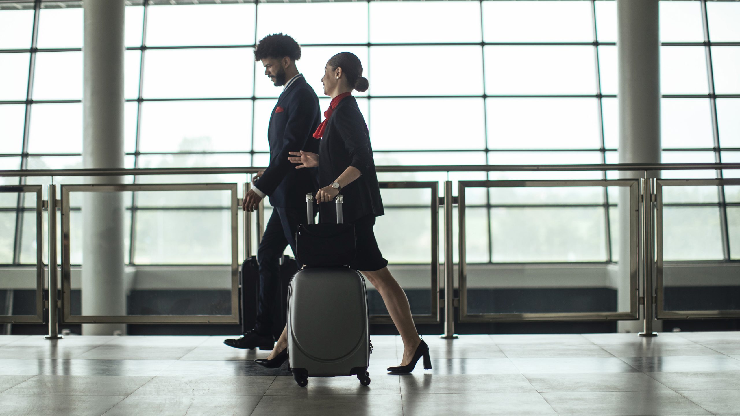 1795769564 Aircrew members carrying luggage inside an airport.