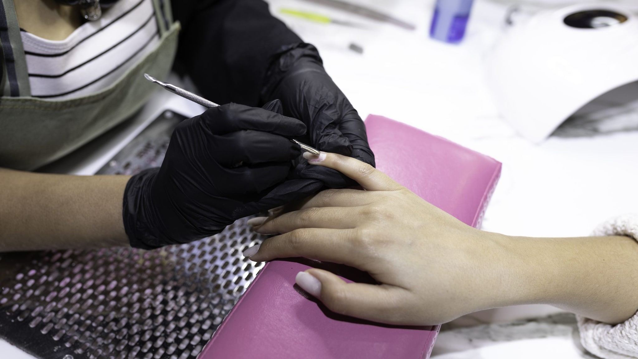 Nail Technician Manicure Nail technician wearing gloves and performing manicure over ventilated table
