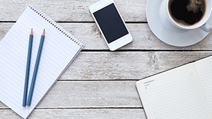 Small Business Resource Guide View of a desktop with a notebook, pencils, cell phone and cup of coffee