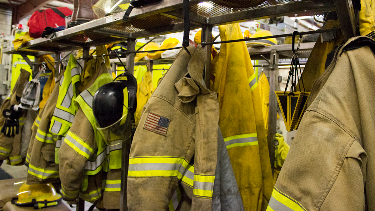 NIOSH FF Center Photo showing multiple Firefighter coats, hats, equipment hanging up.