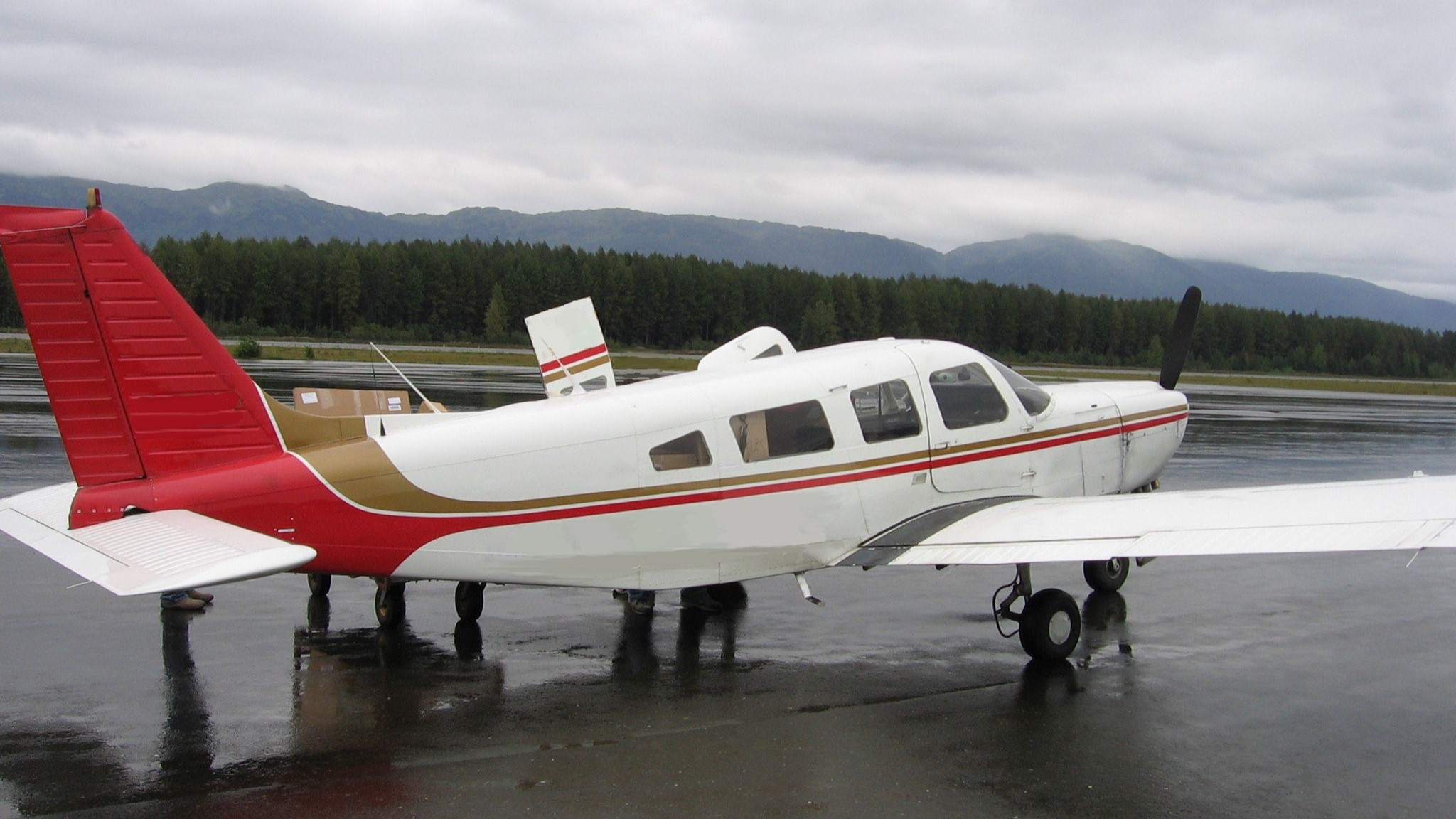 Alaska Aviation Thumbnail Small commuter plane with red stripe down the side on the runway under cloudy skies