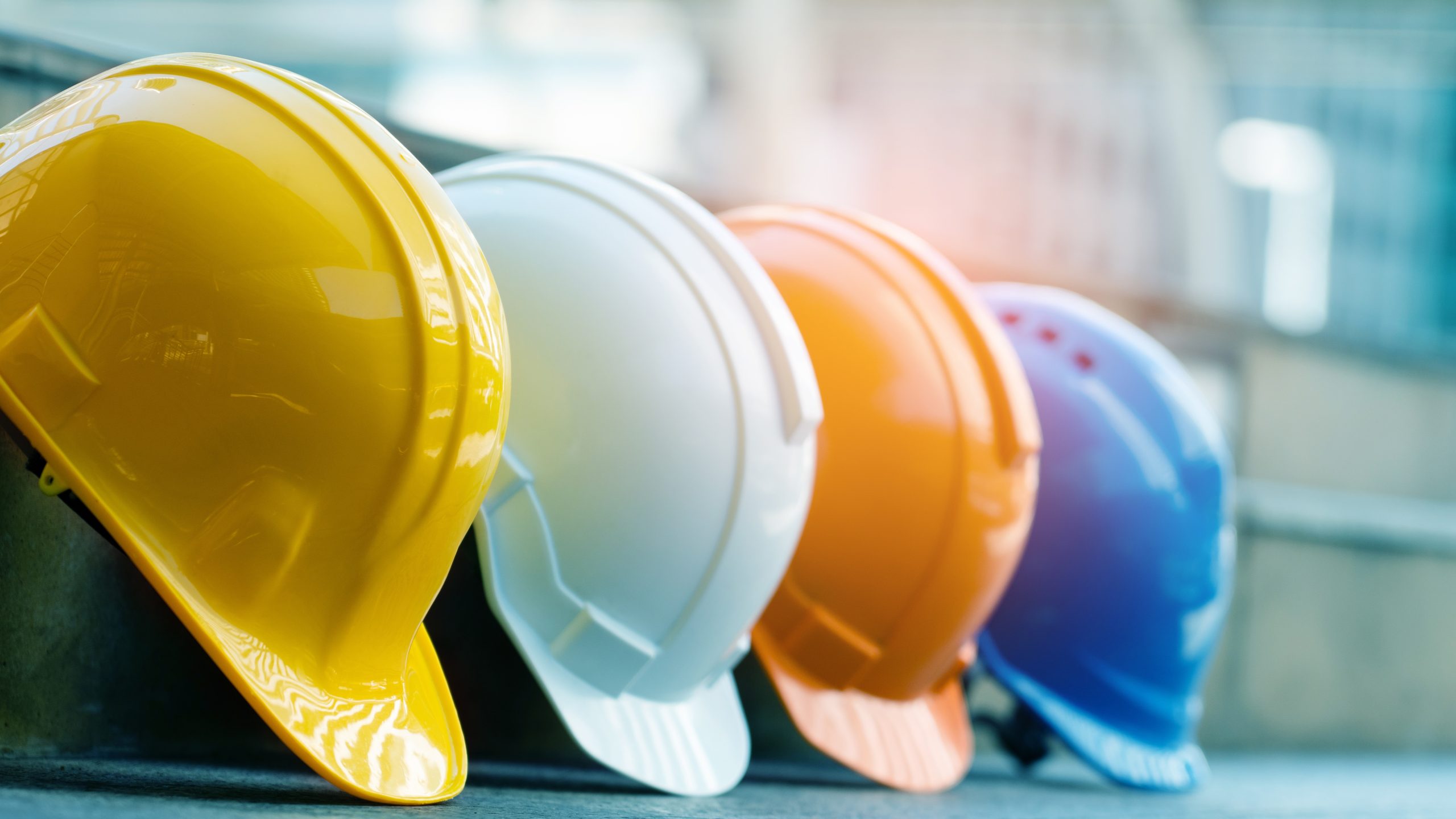 Photo of four construction helmets in different colors (yellow, white, orange and blue)