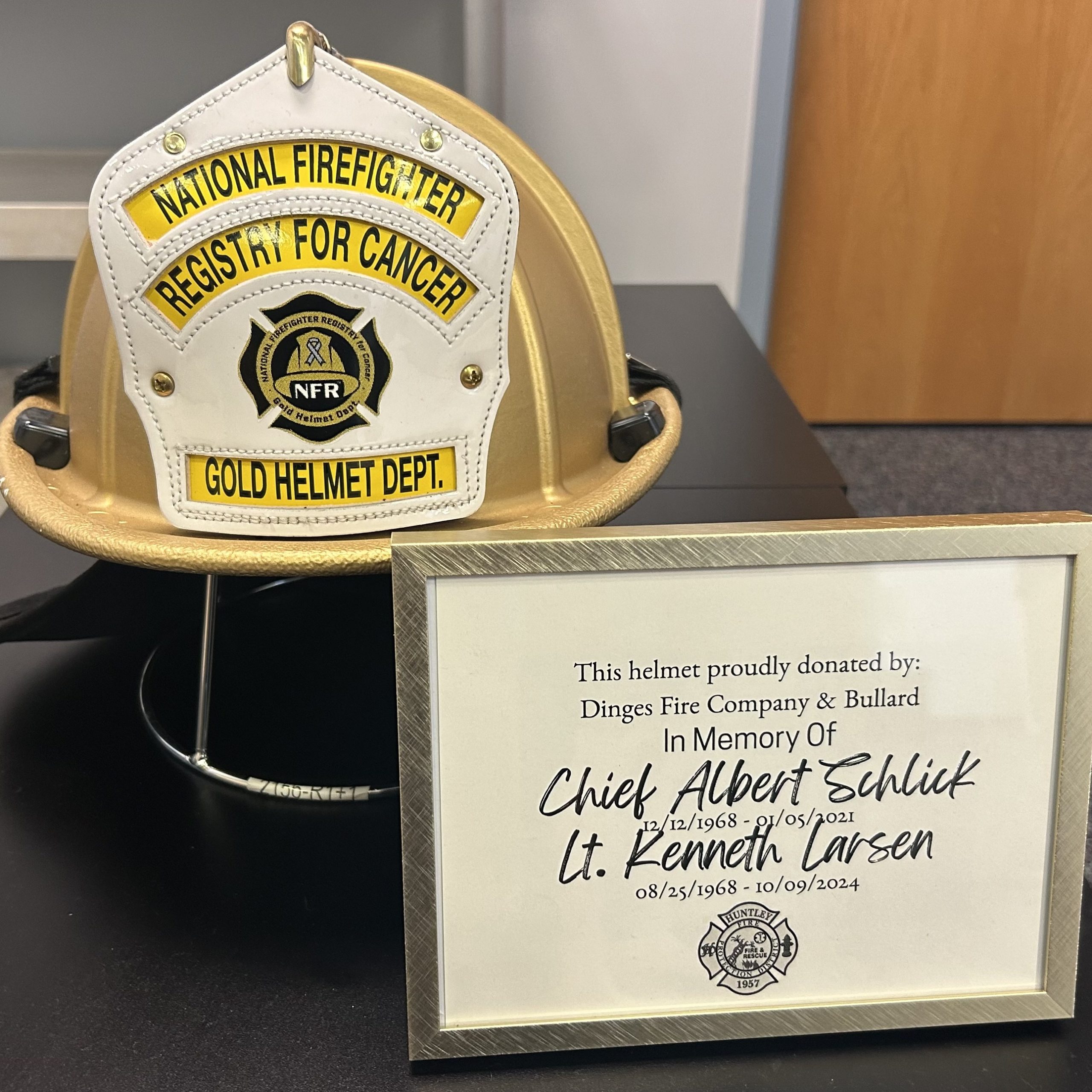 NFR Gold Helmet with plaque saying helmet was proudly donated in memory of Chief Albert Schlick and Lt. Kenneth Larsen