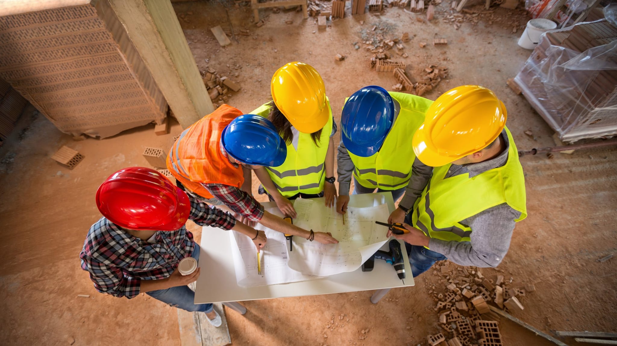 — title missing — five people in hard hats standing looking at plans together