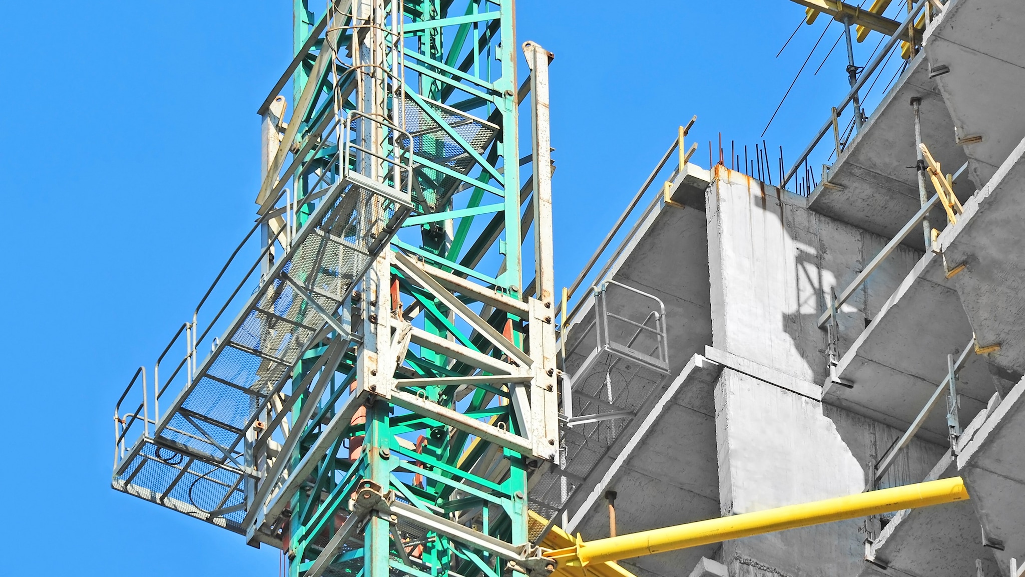 MastClimbingWorkPlatform Mast climbing work platform is next to a building under construction.