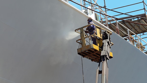 Worker painting ship hull using airbrush. Credit: iStock / Getty Images Plus