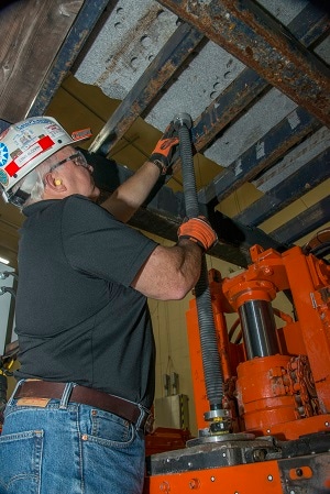 Photograph of researcher performing laboratory testing of the new collapsible drill still enclosure prototype.