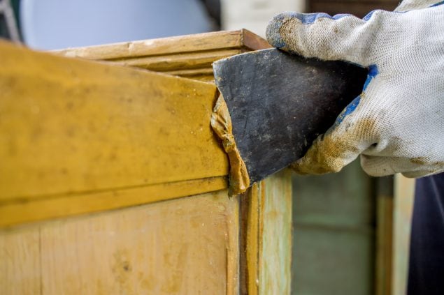 Worker's hand refinishing wood board.