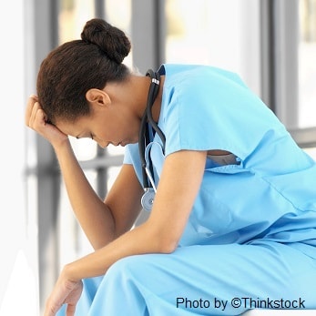 skd238146sdc A nurse sits with her hand on her forehead