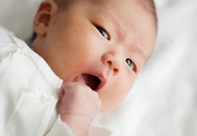 signs-hungry-full-1.jpg An infant turning her head to the side and putting her hand near her mouth.